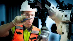 An engineer programs or repairs a high-tech industrial robot. This smart factory uses AI-driven automation for advanced manufacturing or microchip production.