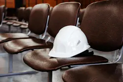 Construction helmet on an empty seat in a conference room.