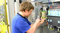 Young apprentice assembles components and cables in a factory in a switch cabinet - workplace industry with future