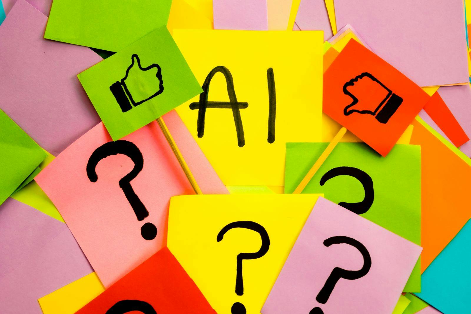 Yellow sticky note with black lettering saying AI with like and dislike flag on colored papers with question marks, concept of acceptance and dislike about the AI and the future