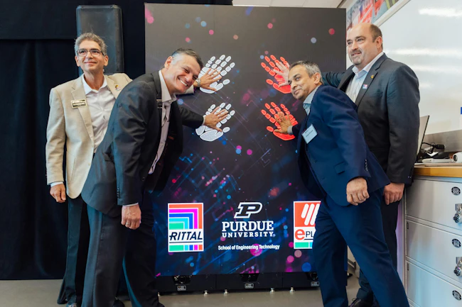 Four officials from Purdue, Rittal and Eplan placing their hands on a wall promoting their new engineering lab